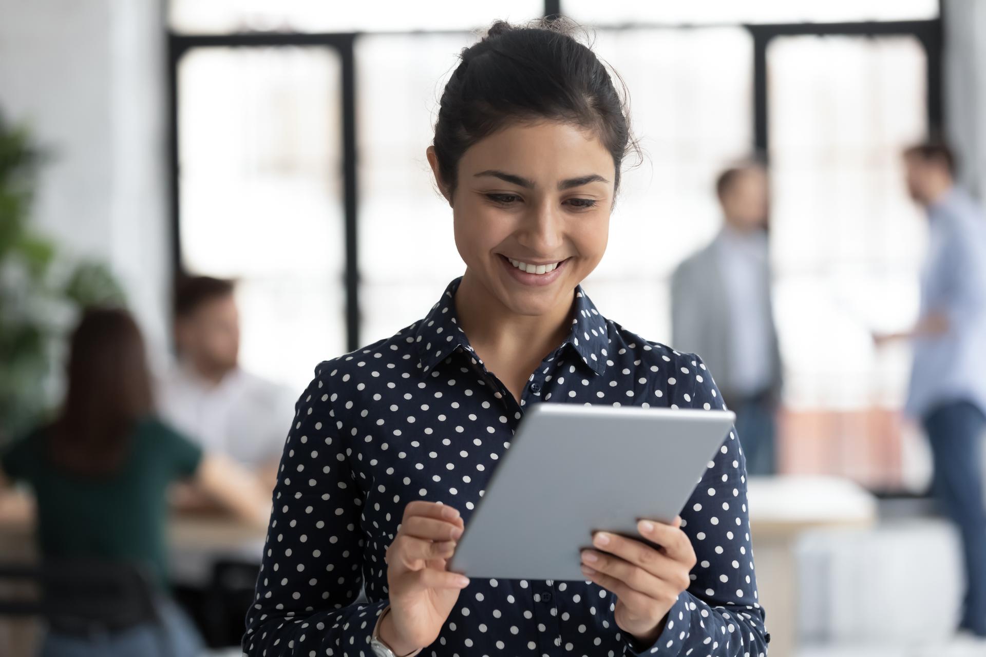 Indian employee holding tablet device surfing web in office